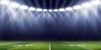 Image of a football field with stadium lights in the background