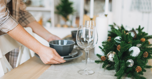 Person setting the table with holiday decorations and plates