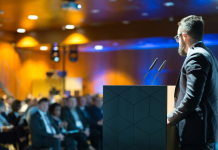 Don’t Book Your Next Speaker Until You Hear This Keynote speaker onstage at a podium addressing a group of business professionals