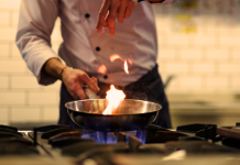 Speakers Who Sizzle: Meet the Talented Cast of “The Bear” A chef in a kitchen cooking with a pan