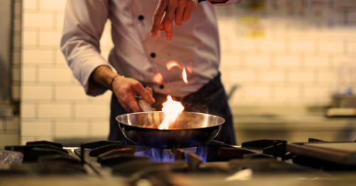A chef in a kitchen cooking with a pan