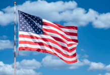 America 250: Experts on America’s Founding and Future American flag against backdrop of blue sky and clouds