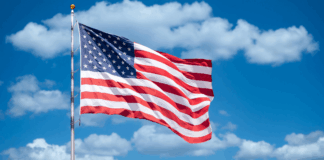 American flag against backdrop of blue sky and clouds