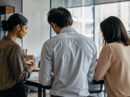Leading Through Uncertainty: Speaker Strategy for 2026 Events Three business professionals engaged in earnest discussion about organizational strategy in a modern office environment