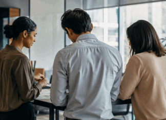 Leading Through Uncertainty: Speaker Strategy for 2026 Events Three business professionals engaged in earnest discussion about organizational strategy in a modern office environment