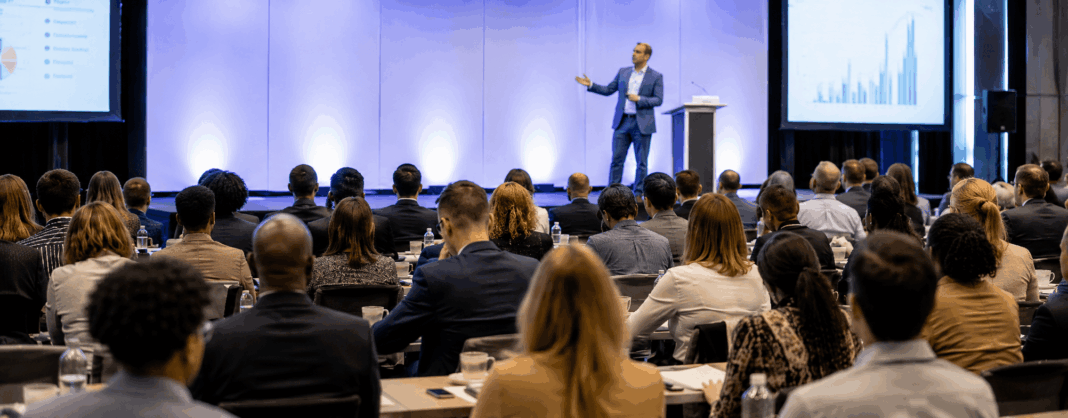 Speaker Customization Evaluating Depth Before Booking Professional event setting with engaged audience listening to a speaker on stage, representing the high stakes and importance of speaker selection and customization.