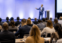 Speaker Customization: Evaluating Depth Before Booking Professional event setting with engaged audience listening to a speaker on stage, representing the high stakes and importance of speaker selection and customization.