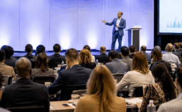 Speaker Customization: Evaluating Depth Before Booking Professional event setting with engaged audience listening to a speaker on stage, representing the high stakes and importance of speaker selection and customization.